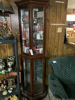 Front and slight side view of tall wooden china cabinet with glass panels showing location and display of contents.