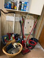 Wide shot of cleaning supplies, mop, bucket with wringer, ironing board and vacuum