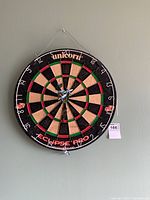 Front view of the Unicorn Eclipse Pro 2 dartboard with darts grouped at the bullseye area, showing the face and numbering clearly.