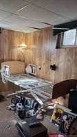 Full view of MedMizer adjustable hospital bed in basement setting, showing metal frame with wheels and wood-grain headboard and footboard.