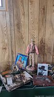 Full view of collection with John Wayne figurine, books, calendars, playing cards, photo, and bar tool box