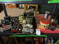 Overview of lot showing metal replica cars, Coca Cola tins, mini cars in display case, chalkware plaques, and collector cards on shelving unit.