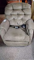 Front view of beige power recliner chair showing plush cushioned backrest, armrests, and control remote on seat.