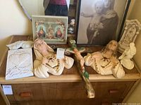 Overview of lot showing Mary and Jesus chalkware busts, cross, religious prints, and plaques arranged on wooden surface