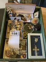 Overview of religious jewelry collection including crucifix pins, medallions, rosary beads, and lockets arranged in boxes and containers.