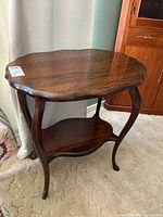 Front angle showing full table with scalloped tabletop, curved legs, and lower shelf.