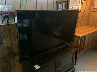 Full view of the Sharp LCD TV on a stand, showing front of the television and black bezel.