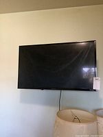 Front view of the black flat screen Sharp television mounted on a wall.