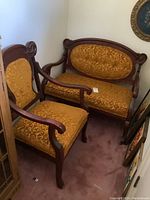 Antique settee and matching chair side by side showing upholstery and wood frame