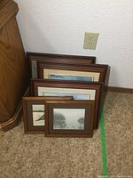 Six framed prints stacked against wall, total of 6 pieces in the lot.