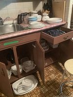 Corning Ware Cornflower Blue pieces including plates, bowls, teapot, coffee pot on countertop and several casserole dishes in cabinet under sink.