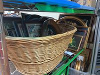 Photo of wicker basket full of framed handiwork, mostly visible are floral and phrase cross stitch pieces