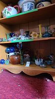 Multiple shelves filled with various hand blown glass items including flowers, vases, decorative balls, and pitchers in Murano style