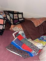 Quilts stacked showing different colors and patterns including floral and solid tones
