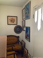 Group shot of multiple framed needlepoint artworks displayed on wall and floor, showing varied sizes and styles
