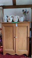 Front view of pine jam cupboard with porcelain knob and decorative vases on top
