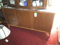 Front view of vintage wooden sideboard showing three drawers on the left and two doors on the right.