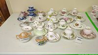 Overview of 20 assorted vintage tea cups with matching saucers displayed on table, various floral patterns and colors