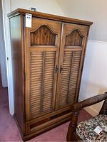 Front view of wood wardrobe with two faux slatted doors and label.