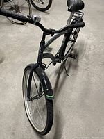 Full side-angle view of the black 26-inch cruiser bike showing the curved frame, front fender, saddle and handlebars.