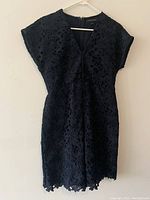 Full view of dark blue Banana Republic dress hanging on a hanger, showing its silhouette and design.