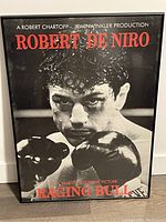 Framed black and white Raging Bull movie poster featuring Robert De Niro in boxing pose with gloves raised.