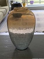 Photo of a gradient colored glass vase on a table with a room background.