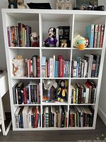Photo of a large white bookshelf filled with books and various decorations, arranged in 12 compartments.