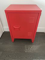 Front view of orange metal cabinet showing single door with ventilation slits and recessed handle.