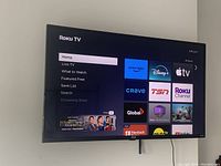 Front view of the wall-mounted 42-inch RCA Roku Smart TV powered on