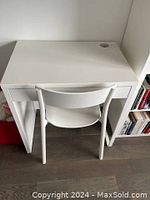 White desk with drawer and chair positioned in front, showing top surface and drawer front.
