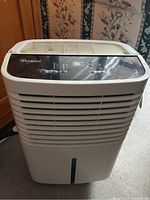 Front view of the white Whirlpool dehumidifier showing air vents and control panel on top.