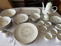 Overview of entire dish set including coffee pot, sugar bowl, creamer, plates, bowls, cups, and saucers on a table.