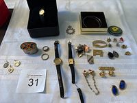 Overview of full lot including watches, charms, ring, earrings, bracelets, brooch, and small box.