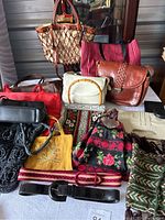 Full view of collection of purses and belts on table showing various styles and materials