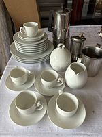 Wide view of espresso set with plates, cups, stainless steel espresso maker, coffee grinder, and cream and sugar jars