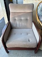 Front view of chair showing seat cushion, tufted back and wood frame