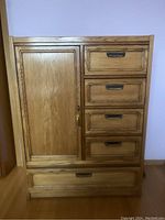 Front view of the tall wooden dresser showing five drawers and one storage cabinet door.