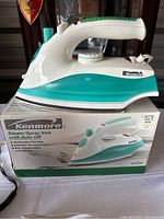 Kenmore steam/spray iron sitting on its original box.