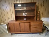 Front view of walnut credenza base with hutch on top against wood-paneled wall