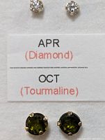 Top view photo showing close up of one pair of diamond earrings and one pair of green tourmaline earrings next to a label indicating APR (Diamond) and OCT (Tourmaline).