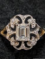 Top-down view of ring showing central emerald-cut diamond in decorative white gold mount