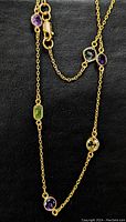 Close-up of necklace chain showing bezel-set stones of various colors and shapes with lobster clasp