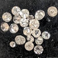 Close-up view of several assorted loose diamonds on a black background, illustrating the cut and clarity of the stones.