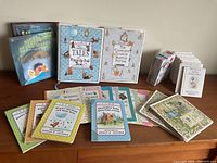 Wide view of the collection laid out with several books standing and many smaller storybooks spread flat showing titles mostly Winnie-the-Pooh themed with Beatrix Potter books featured