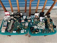 Wide shot of all costume jewelry on two chairs, showing a large assortment of necklaces, earrings, and brooches arranged loosely.