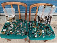 Wide view of assorted costume jewelry spread on two chairs, showing diversity of pieces.