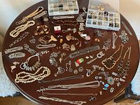 Overhead view of table displaying loose necklaces, bracelets, earrings, pendants, and two compartment trays