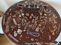 Overview of all jewelry items on round wooden table including necklaces, earrings, brooches, and chains.