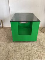 Front view of green cube side table showing glass top and cut-out side opening.